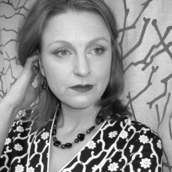 A black and white portrait photo of Elle Brooker, whose website this is, wearing a Japanese patterned black and white dress from Kamikaze and a necklace.